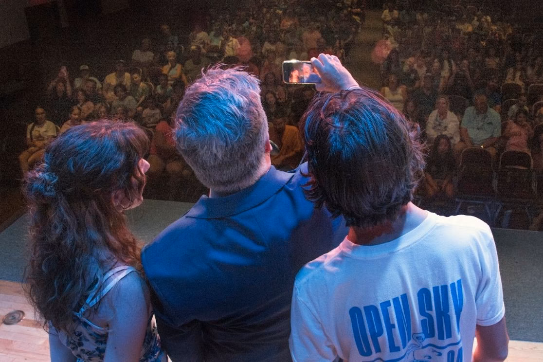 Al Getler and audience volunteers looking out at a full room during a live performance.